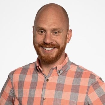 A headshot of AJ Bruno wearing a plaid gray and coral colored shirt.